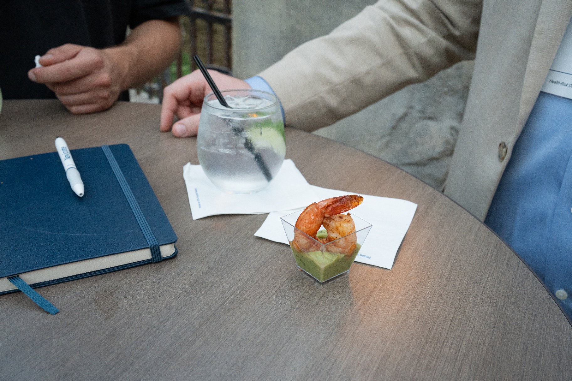Reception detail showing branded notebook, drink, and hors d'oeuvres