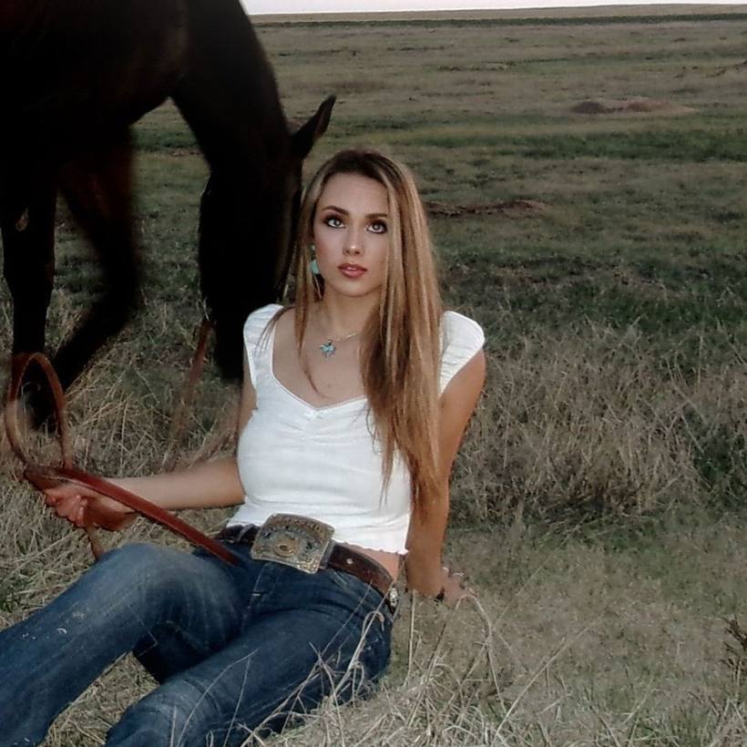 Gwen sitting in a field holding her horse's reins