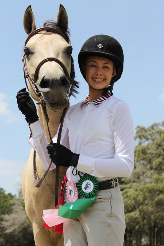 Gwen as a kid in show clothes with a buckskin pony and ribbons